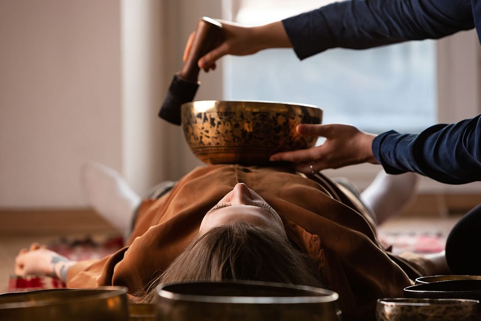 Тибетская поющая чаша на теле человека во время сеанса звукотерапии — вибрации проникают в ткани, улучшают кровообращение и расслабляют мышцы.